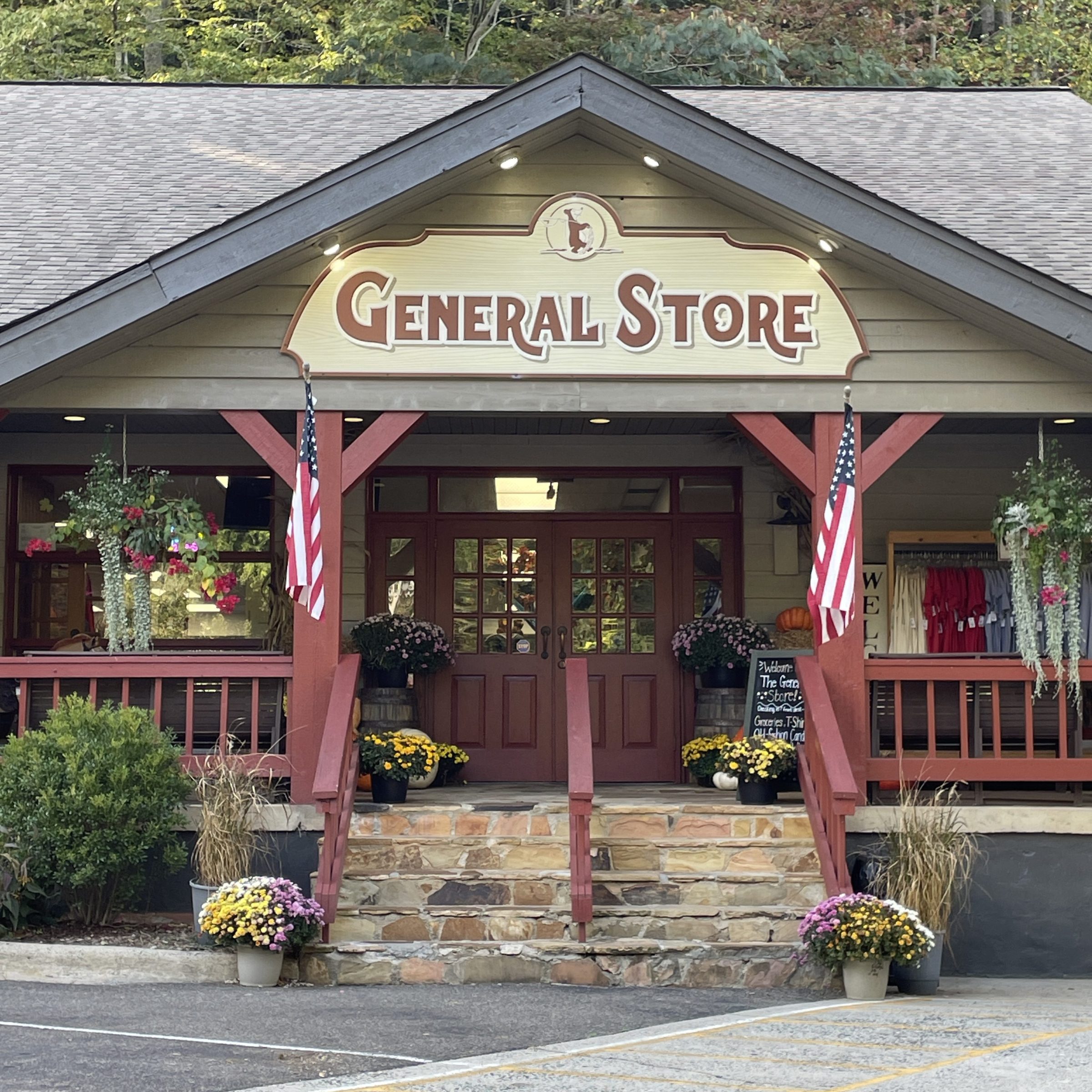 Front of a general store with flags, flowers, and a stone staircase.