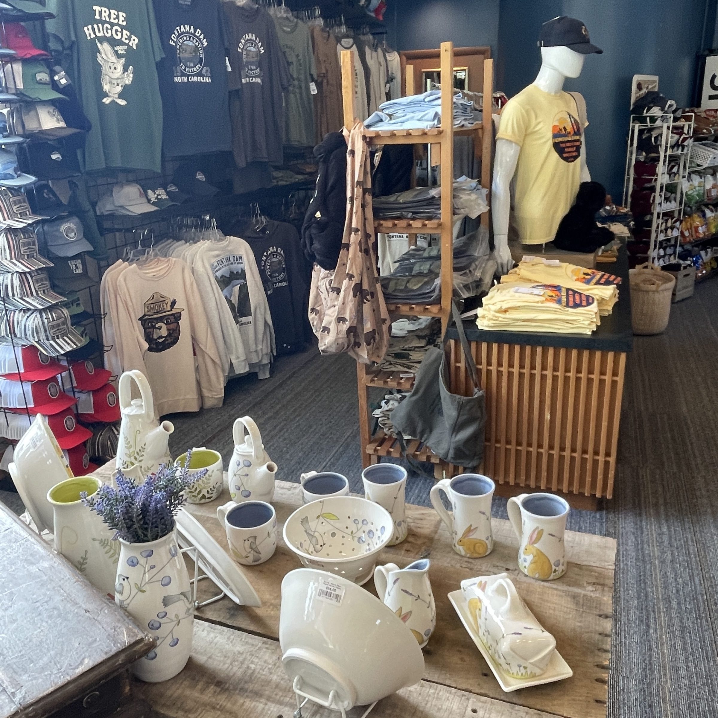 Store interior with pottery on table and clothing displayed on racks.