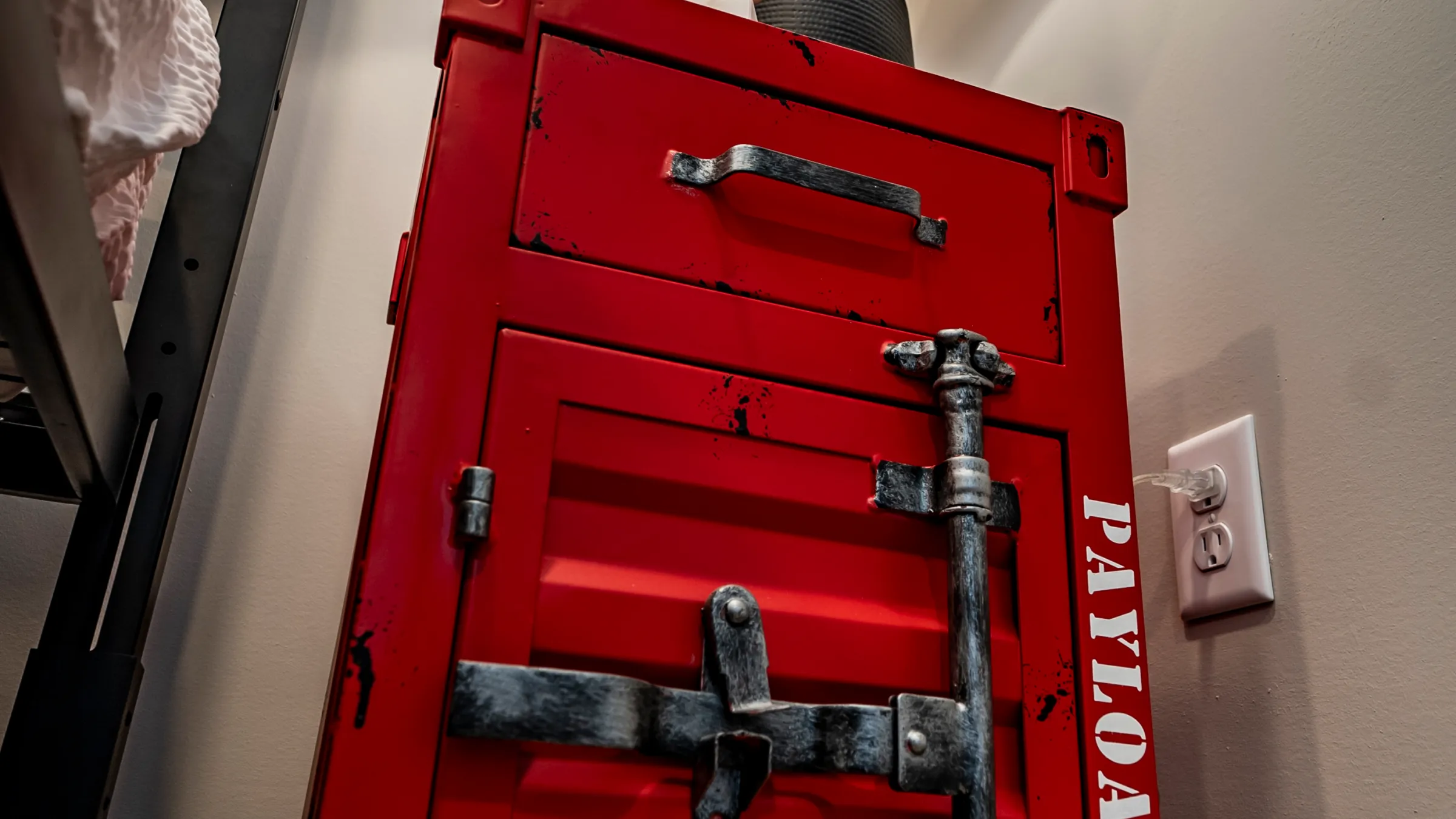 Red industrial cabinet with unique latch, topped with modern lamp and decor.