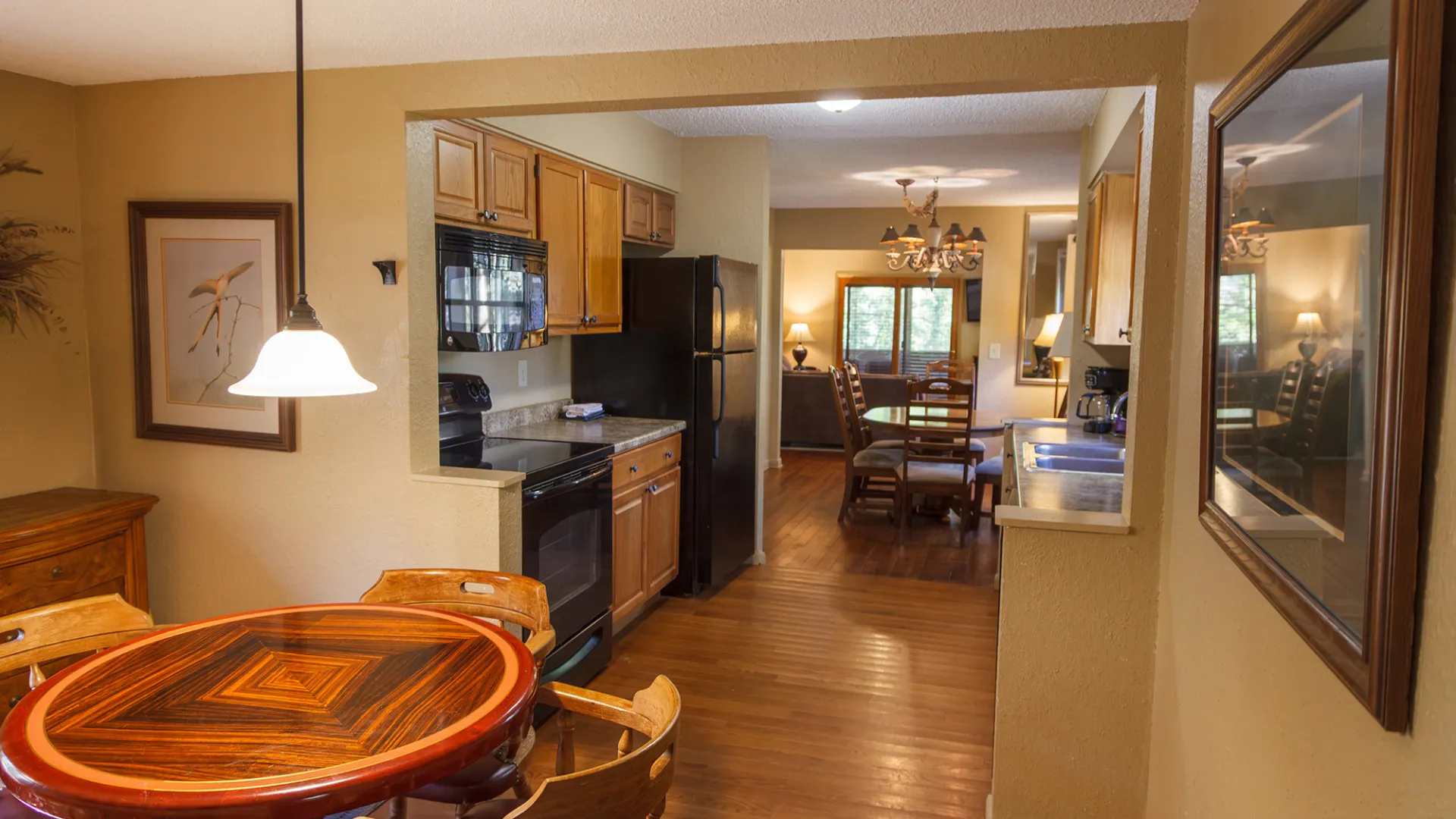 Cozy kitchen and dining area with wooden table, chairs, and pendant lighting.