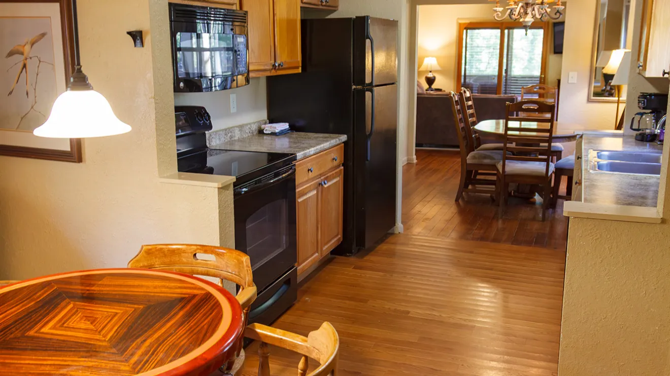 Cozy kitchen and dining room with wooden floors, round table, chairs, cabinets, and appliances.