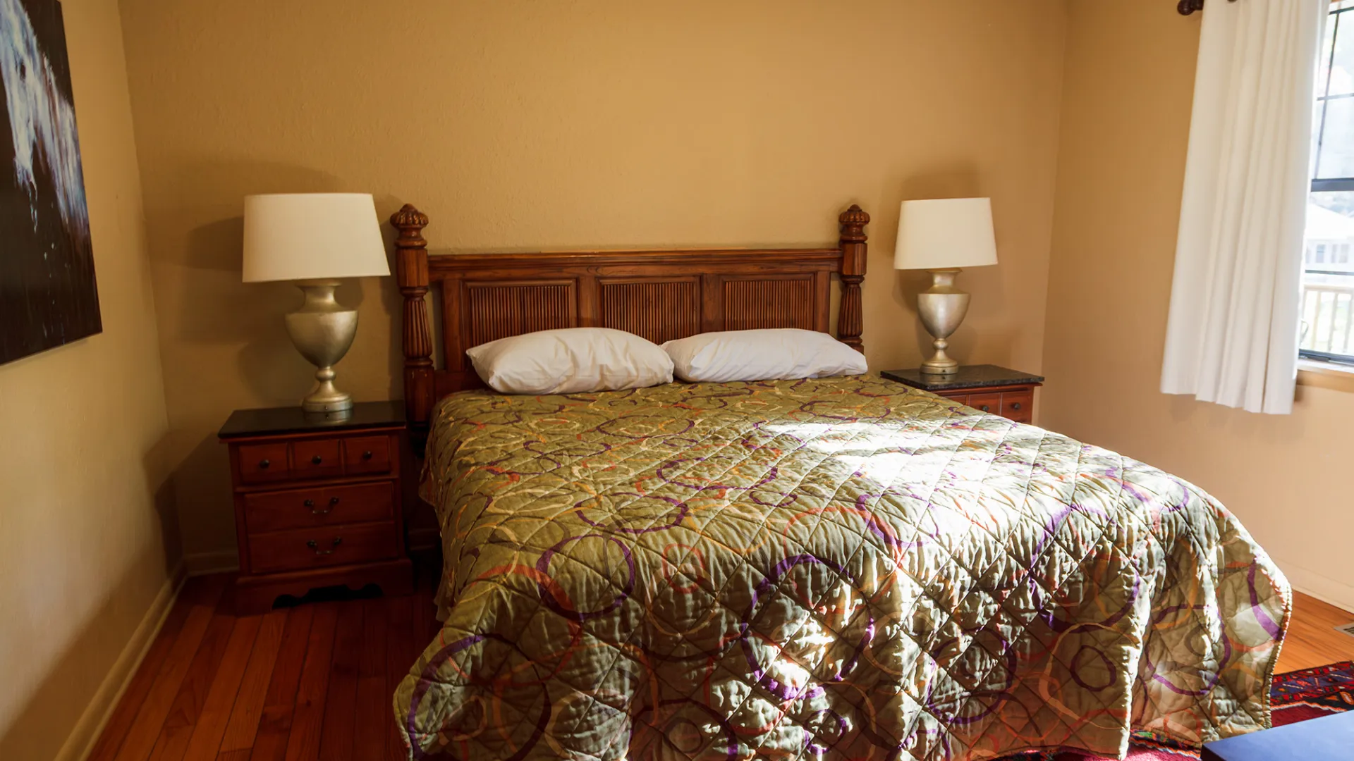 Cozy bedroom with a double bed, two lamps, and wooden furnishings in natural light.