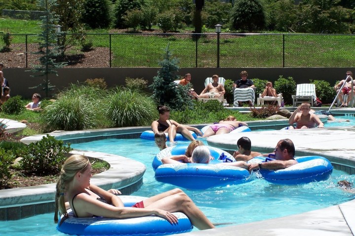 People relaxing on blue inflatables in a lazy river pool.