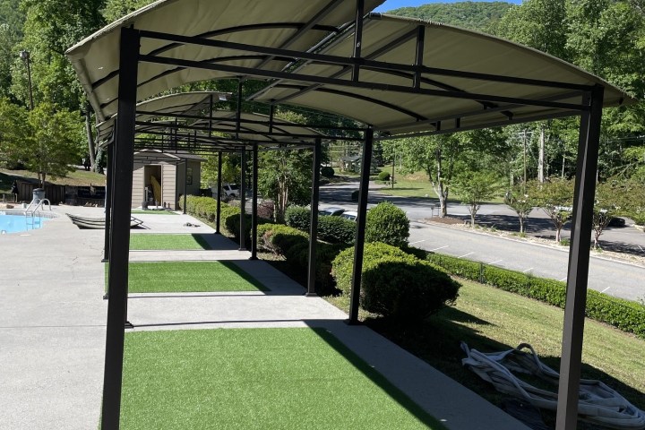 Metal frame structure with green turf beneath on a sunny day.